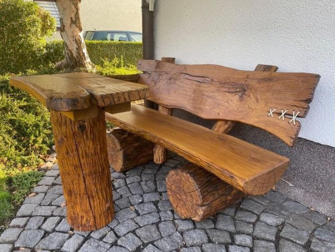 Rustikale Holzbank mit Tisch, gefertigt aus massiven Holzscheiben und -stämmen.