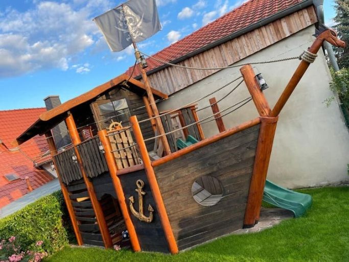Piratenschiff-Spielplatz mit Rutsche, Anker und Piratenflagge im Garten.