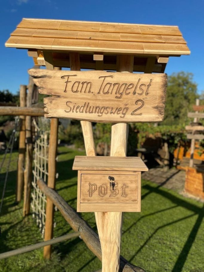 Uriges Holzschild mit Familienname und Briefkasten.
