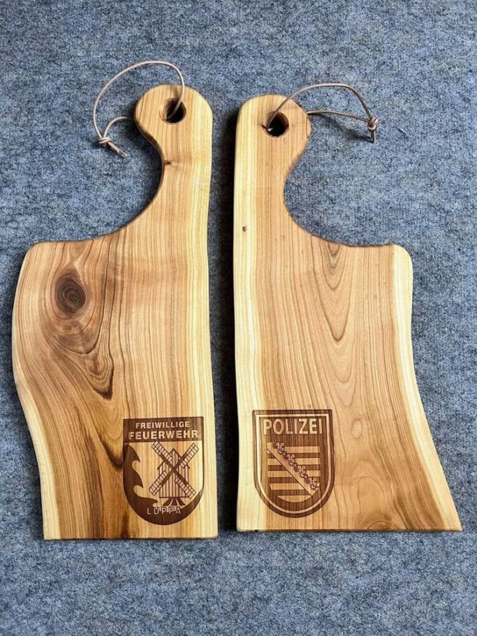 Zwei Holzschneidebretter mit gelaserten Wappen.