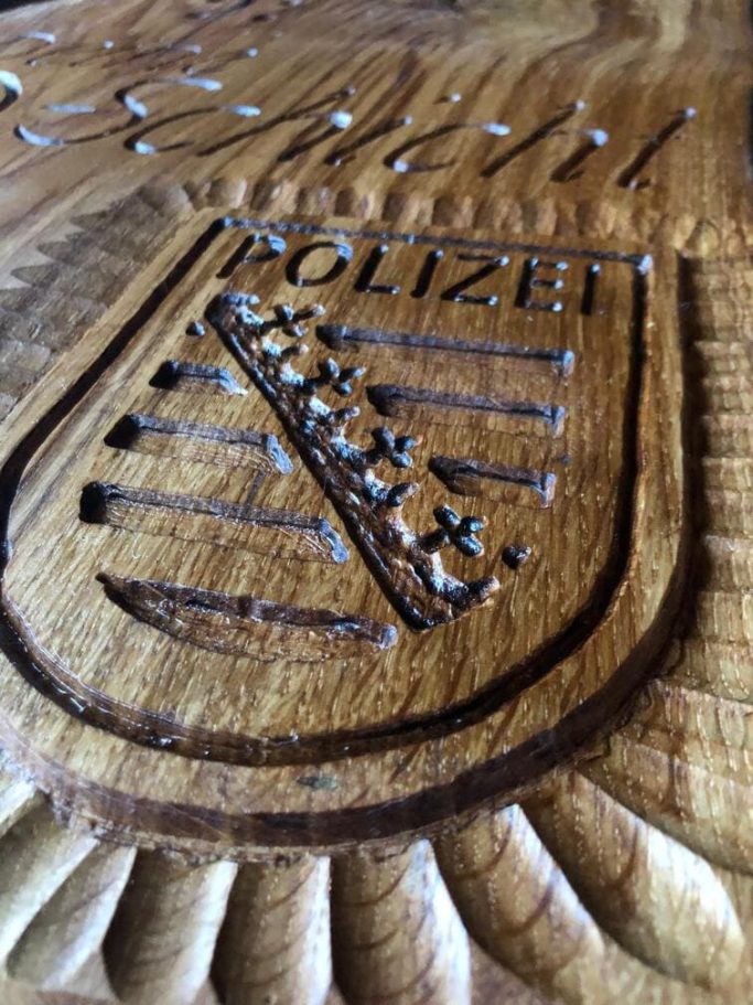 Detailaufnahme eines geschnitzten Holzwappens der POLIZEI Sachsen.