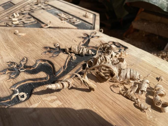 Holzoberfläche mit kunstvollem Schnitzdesign und Holzspänen.